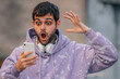 © carballo - young man looking surprised at mobile phone in the street