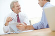 © GR/peopleimages.com - I like these recent developments. Two male business associates sitting at a desk having a meeting.