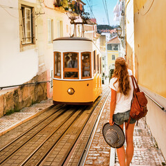 Wall Mural - Traveler woman waiting yellow traditional tram on a street in Lisbon- Portugal