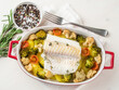 Fish cod baked in the oven with vegetables - healthy diet healthy food. Light white wooden background, top view.