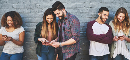 Aufkleber - The net is the new hangout spot. a group of young friends using their wireless devices together outdoors.