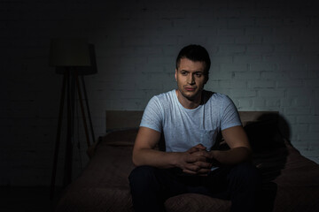 Wall Mural - depressed man in white t-shirt sitting on bed while suffering from ptsd.