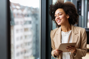 Portrait of a smiling confident african american young businesswoman working with digital tablet