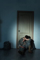 Poster - Soldier with mental disorder sitting near backpack and door at home at night.