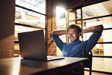 Aufkleber - Another deadline met with ease. a handsome young male designer looking relaxed while working late in his office.