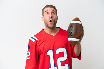 Poster - Young caucasian man playing rugby isolated on white background looking up and with surprised expression