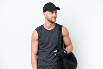 Wall Mural - Young blonde sport caucasian man with sport bag over isolated white background looking side