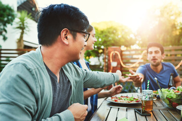 Leinwandbilder - Heres a slice for you bro. two young man passing a pizza slice to each other around a table in an outside gathering with friends.