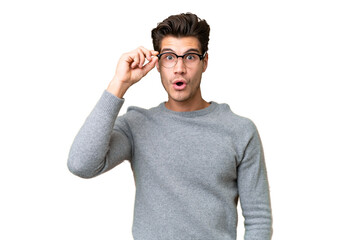 Wall Mural - Young handsome caucasian man over isolated background with glasses and surprised