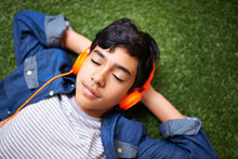 Headphones, Music And Boy Relax On Grass With Eyes Closed Outdoors On Holiday, Free Time And Weekend. Calm, Peace And Face Of Kid In Garden Listening To Song, Track And Streaming Audio For Happiness