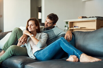 Wall Mural - Our future looks really bright. Full length shot of an affectionate young couple relaxing on their sofa at home.