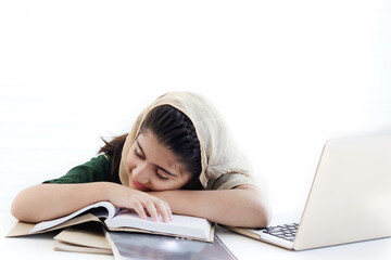 Wall Mural - Adorable Muslim sleepy girl student wearing traditional hijab taking a nap, feeling bored, tired during studying and doing homework on table, kid reading book on white background, child education.