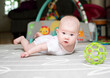Cute Caucasian baby girl doing tummy time on the play mat looking at the camera