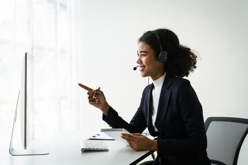 Wall Mural - African american woman in headset reads data on computer while talking with customer in call center