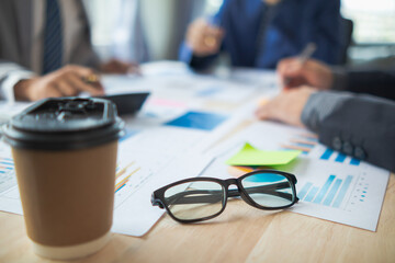 Glasses with black frames placed on a desk in office are eyeglasses that are prepared for wearing when looking at resolutions because eyeglasses will help adjust eyesight to be sharper in vision