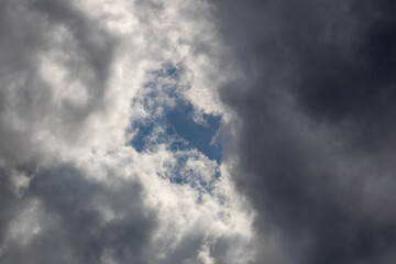 Looking up at gray and white clouds against blue sky