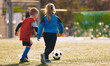 © matimix - Little boy and girl running and kicking soccer ball. Football lesson for school boys and girls