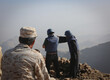 Yemeni soldier looks at two journalists reporting the event in Taiz, Yemen