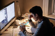 © Marius V/peopleimages.com - Man, studying and headache in night by computer for test, assessment or stress in college dorm room. Male university student, tea cup or burnout with anxiety, fatigue or tired with books for learning
