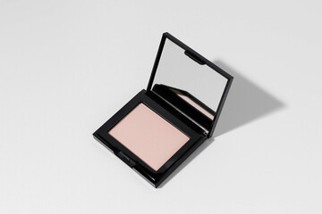 Pink or peach face powder with mirror with shadow from direct light on white isolated background. Concept of decorative cosmetics for face makeup, cosmetic product. Image for your design.