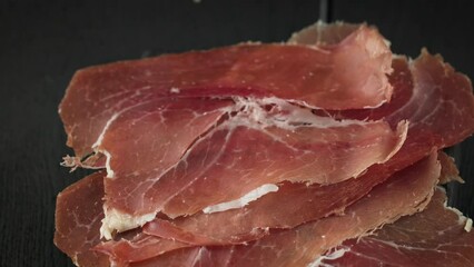 Poster - sliced spanish iberico ham on black wooden table background