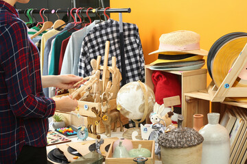 Wall Mural - Woman holding wooden figure near table with different stuff indoors, closeup. Garage sale