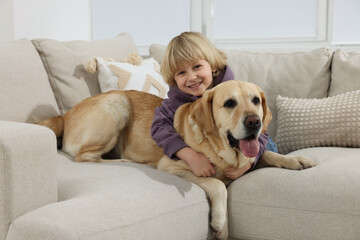 Poster - Cute little child with Golden Retriever on sofa at home. Adorable pet