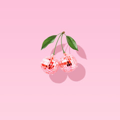 Modern retro composition made of decorative disco balls like cherries on a pastel pink background. The concept of minimal entertainment. Flat lay. Contemporary style. Creative art, minimal aesthetics.