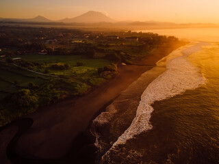 Wall Mural - Aerial view of beach with Agung volcano, warm sunrise or sunset tones and ocean in Bali