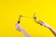 Hands holding slingshot with banana on a yellow background