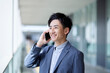 20代日本人ビジネスマンがスマートフォンを使用して仕事をしている春のイメージ