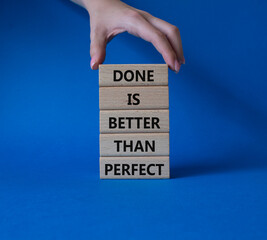 Wall Mural - Done is better than Perfect symbol. Wooden blocks with words Done is better than Perfect. Beautiful blue background. Businessman hand. Business and Done is better than Perfect concept. Copy space.