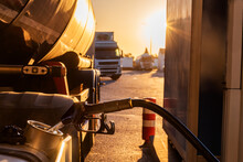 Filling The Fuel Tank Of A Truck At A Gas Station, With Several Trucks In The Background.