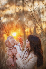 Portrait of baby and mother. Mom and daughter. Girl in a coat and beret. Sunset. Early spring. Autumn. Vintage. Fashion girl. Mom kisses her daughter. An evening walk. Cute little girl in the spring f