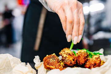 woman chef cooking chicken wings in a sauce in the kitchen