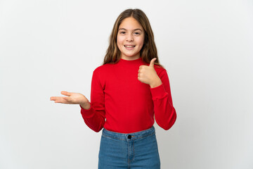 Wall Mural - Little girl over isolated white background holding copyspace imaginary on the palm to insert an ad and with thumbs up