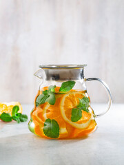 Wall Mural - Fruit tea with oranges, mint  in a glass kettle ( teapot) on white