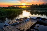 Fototapeta Pomosty - Evening landscape with an old rustic wooden pier and old boats at sunset on the Dnieper Delta