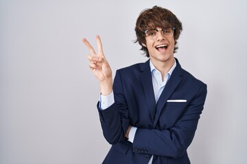 Canvas Print - Hispanic business young man wearing glasses smiling with happy face winking at the camera doing victory sign with fingers. number two.