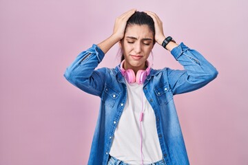 Wall Mural - Young beautiful woman standing over pink background suffering from headache desperate and stressed because pain and migraine. hands on head.