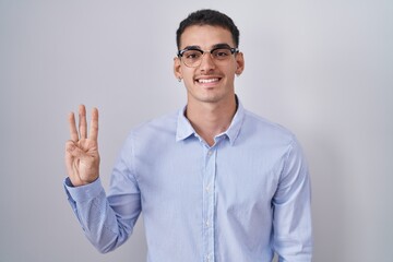 Wall Mural - Handsome hispanic man wearing business clothes and glasses showing and pointing up with fingers number three while smiling confident and happy.