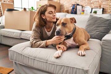 Wall Mural - Young caucasian woman smiling confident lying on sofa with dog at new home