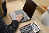 Fototapeta  - Kobieta blondynka przy biurku z laptopem i kalkulatorem 