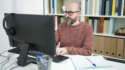 Poster - Young bald man student using computer studying at university classroom