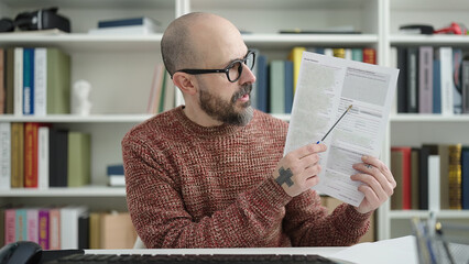 Poster - Young bald man student showing document speaking at university classroom