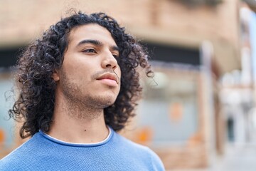 Sticker - Young latin man looking to the side with serious expression at street