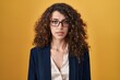 © Krakenimages.com - Hispanic woman with curly hair standing over yellow background relaxed with serious expression on face. simple and natural looking at the camera.