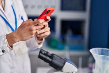Young hispanic woman scientist using smartphone at laboratory