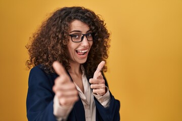 Sticker - Hispanic woman with curly hair standing over yellow background pointing fingers to camera with happy and funny face. good energy and vibes.