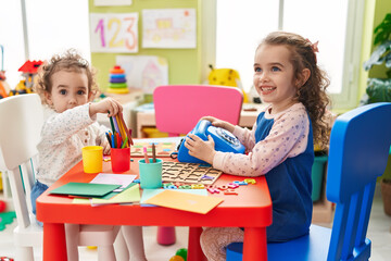 Wall Mural - Adorable girls playing telephone toy sitting on table at kindergarten